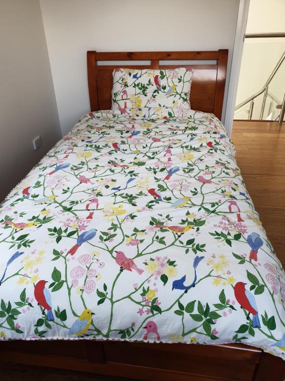 a bed with a bedspread with birds and flowers at The Garden House in Sydney