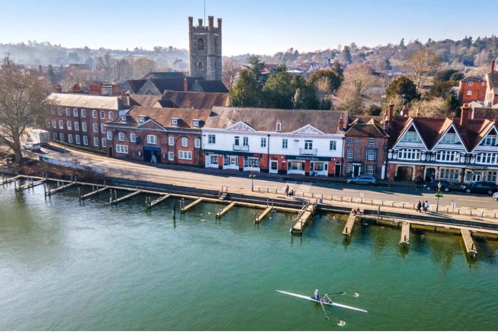 a person in a boat in the water next to a pier at Picturesque Thameside Apartment in Henley on Thames