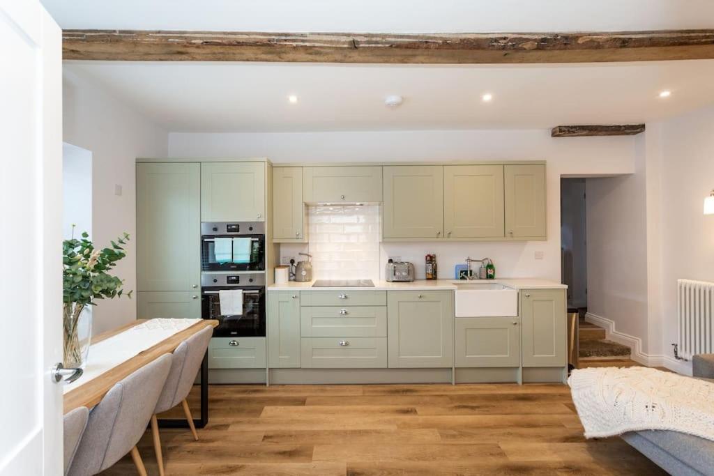 uma cozinha com armários brancos e piso em madeira em The Old Vet’s House em Masham