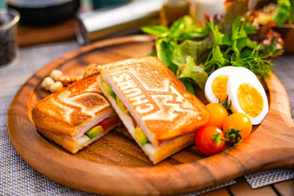 a sandwich and eggs on a wooden plate with vegetables at ASOBI HACK 