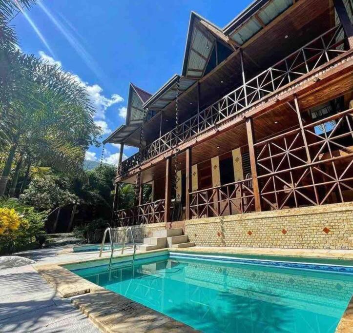 a house with a swimming pool in front of a building at Villa vista del manantial in Concepción de La Vega