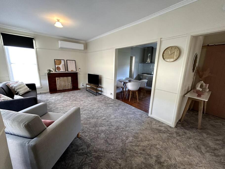 a living room with a couch and a clock on the wall at Shepparton House in Shepparton