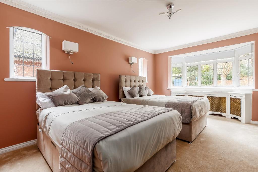 twee bedden in een slaapkamer met oranje muren en ramen bij Traditional Family House Near Beach -Great Garden! in Bournemouth