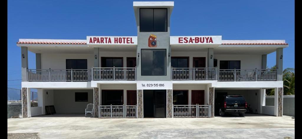 een groot wit gebouw met een auto voor de deur bij Aparta Hotel Esa Buya in San Fernando de Monte Cristi