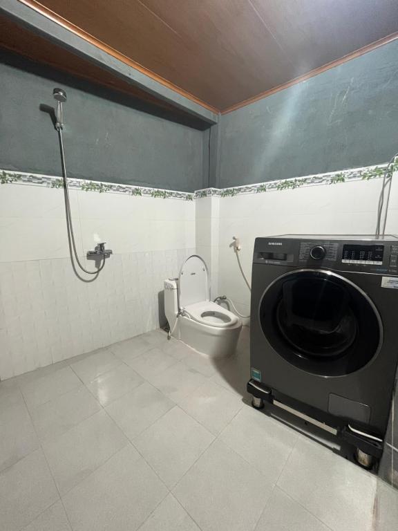 a bathroom with a washing machine and a toilet at Nhà Sàn Bên Suối in Buôn Ðũng