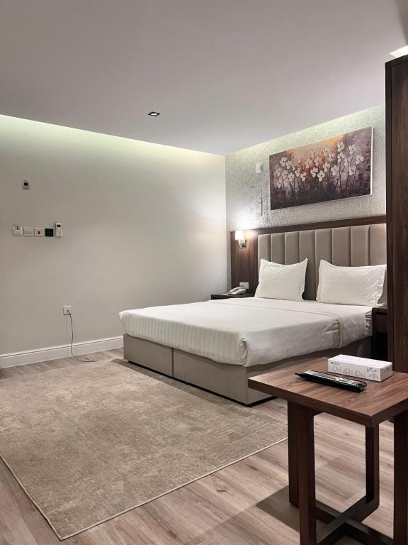 Un dormitorio con una cama grande y una mesa. en Amwaj Alshatie Furnished Units, en Dammam