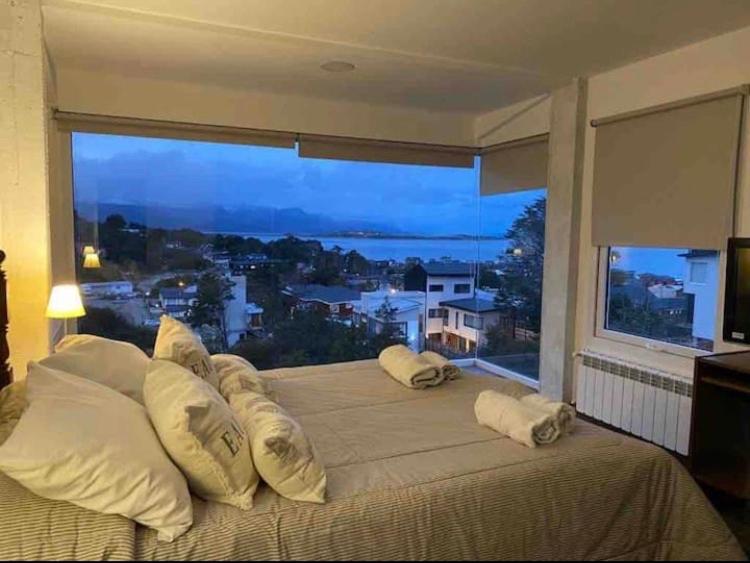 a large bed in a bedroom with a large window at Casa Fin del Mundo in Ushuaia