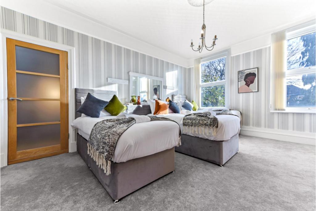 una camera con due letti e un lampadario a braccio di Peaceful and Radiant 3BR Flat a Londra