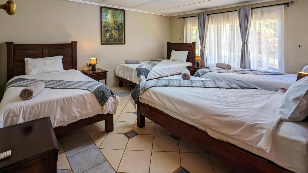 a bedroom with two beds and a window at Room in Villa - Zambezi Family Lodge - Leopard Room in Victoria Falls