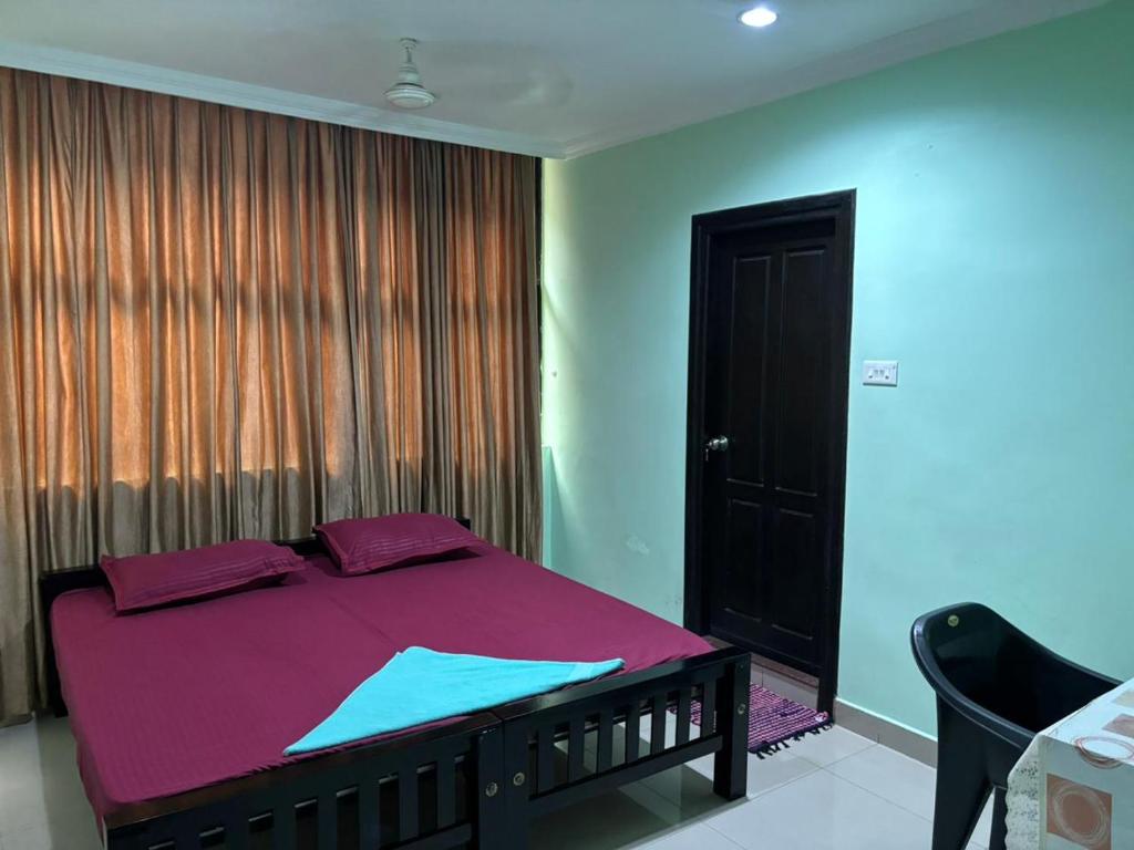 Un dormitorio con una cama con sábanas moradas y una ventana en PRARTHANA RESIDENCY, en Attingal