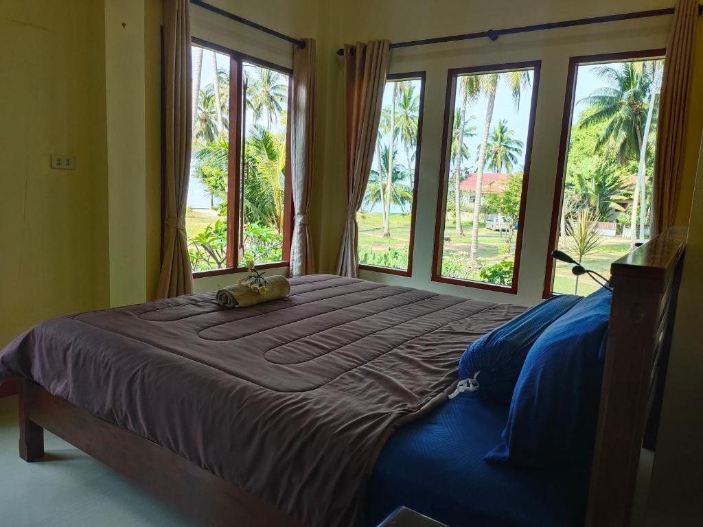 a bedroom with a large bed with large windows at Links Sunset Beach House in Amphoe Koh Samui