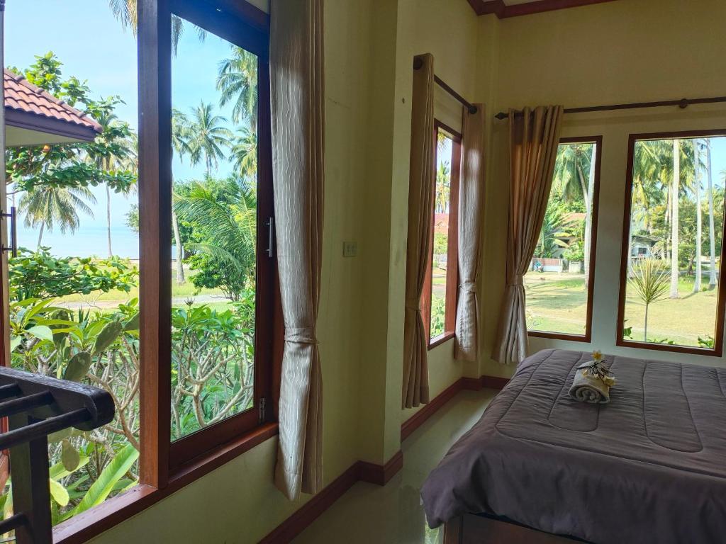 een kamer met een bed en ramen met uitzicht bij Links Sunset Beach House in Nathon Bay