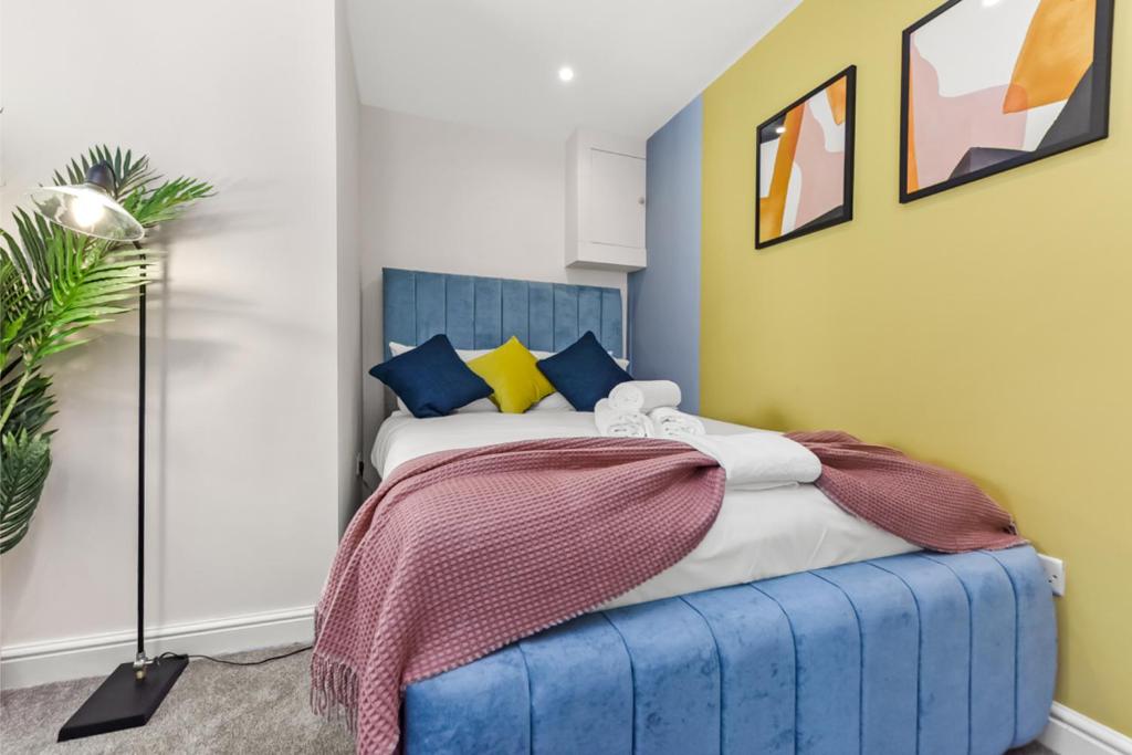 a bedroom with a bed with a blue headboard at Stylish and Snug Studio in Enfield
