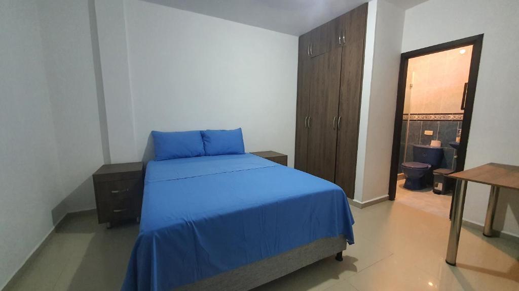 Schlafzimmer mit einem Bett mit blauer Bettwäsche und einem Tisch in der Unterkunft Kiosco Azul - Apartamento amoblado cerca al mar in Ríohacha