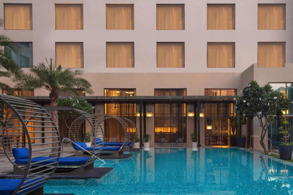 un hotel con piscina con sillas y un edificio en Courtyard by Marriott Agra en Agra