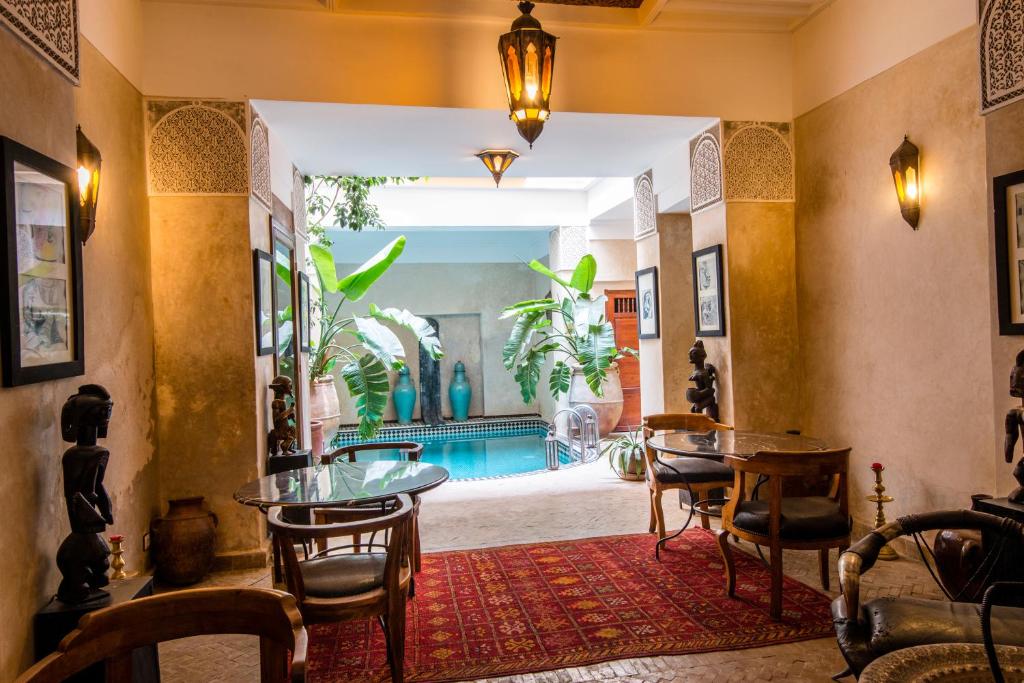 um quarto com mesas e cadeiras e uma piscina em Riad dar Ourika em Marrakech