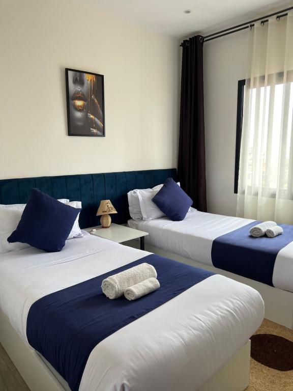two beds in a room with blue and white at Yvanka Appart'City Antsirabe in Antsirabe