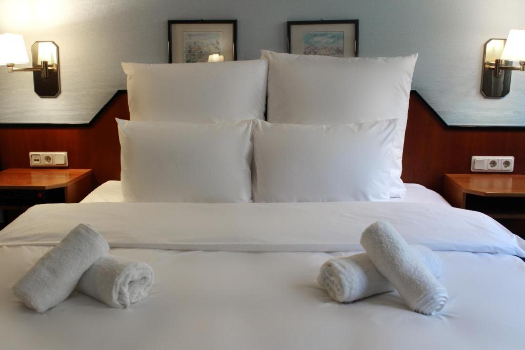 a bedroom with a white bed with towels on it at Hotel Mozart Bonn in Bonn