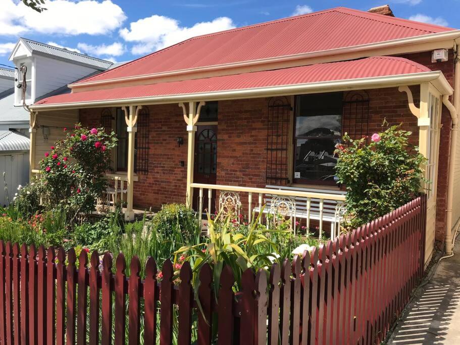Melville Heritage Cottage, Hobart CBD في هوبارت: منزل بسقف احمر وسياج