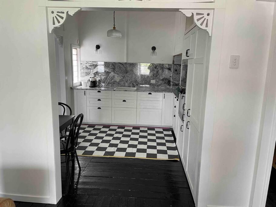 a kitchen with a black and white checkered floor at Comfy Queenslander Cottage in Brisbane