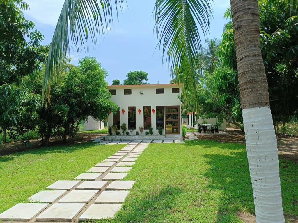 a house with a palm tree in front of it at Rancho Lyon Playa Costa Azul in Sonsonate