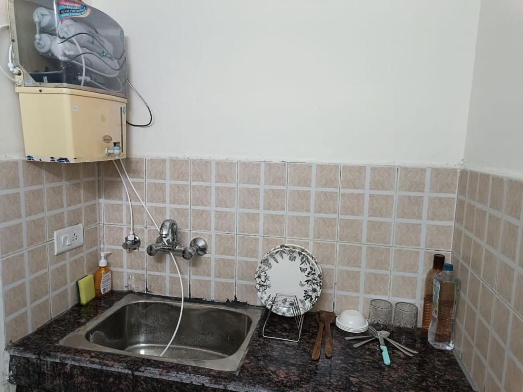 a kitchen with a sink and a tiled wall at ABP Studio's in Ghaziabad