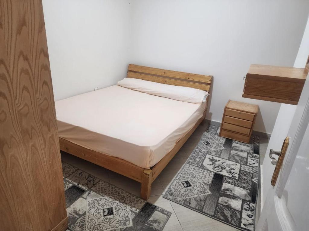 um pequeno quarto com uma cama e uma porta de madeira em شقه الهاني em Marsa Matruh