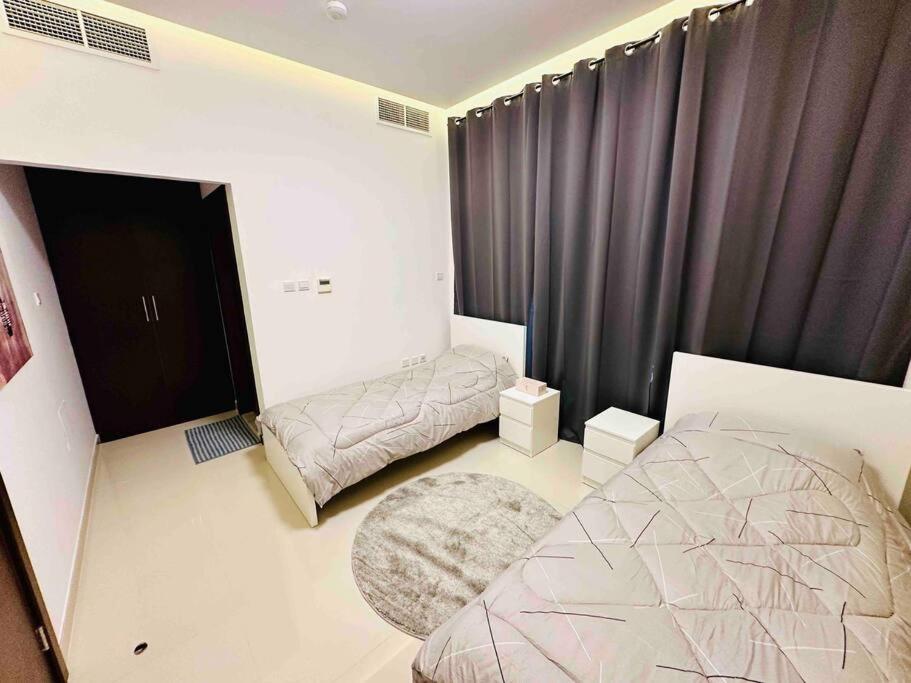 1 dormitorio con 2 camas y una ventana con cortinas en Ocean View Villa, en Fujairah