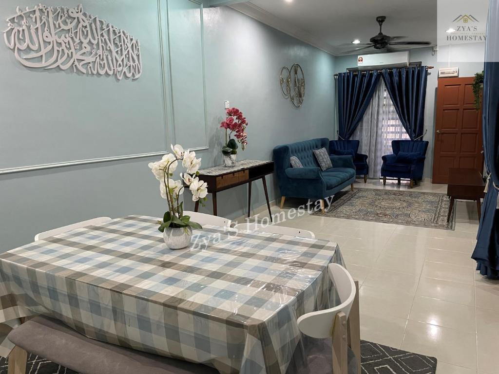 a dining room with a table and blue chairs at Zya'S Homestay Gong Badak in Kampong Bukit Berangan