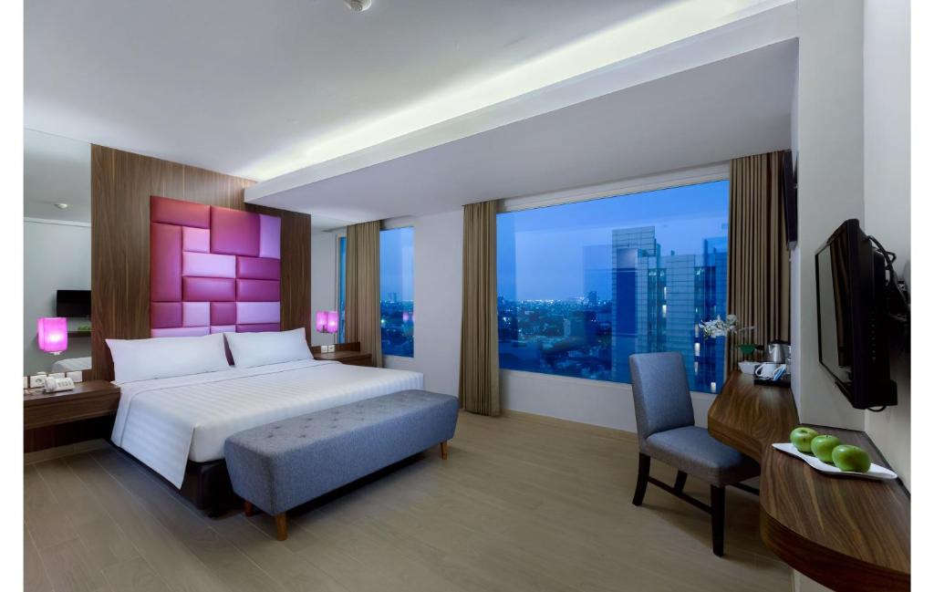 Dormitorio con cama, escritorio y TV en Quest Hotel Darmo - Surabaya by ASTON en Surabaya