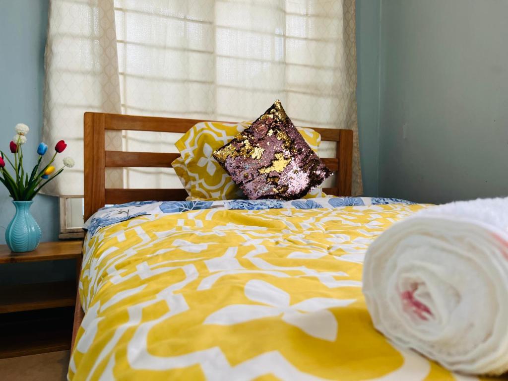 1 cama con edredón y almohadas de color amarillo y blanco en Departamento vacacional en Puyo, en Puyo