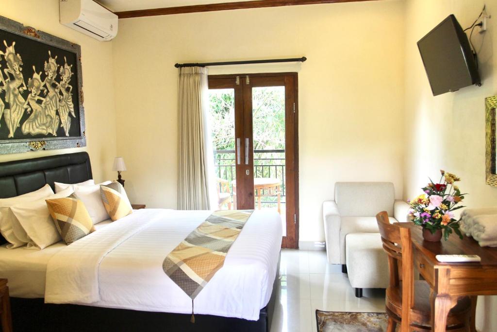 a bedroom with a bed and a chair and a television at Guesthouse Gusti Putu Oka in Ubud