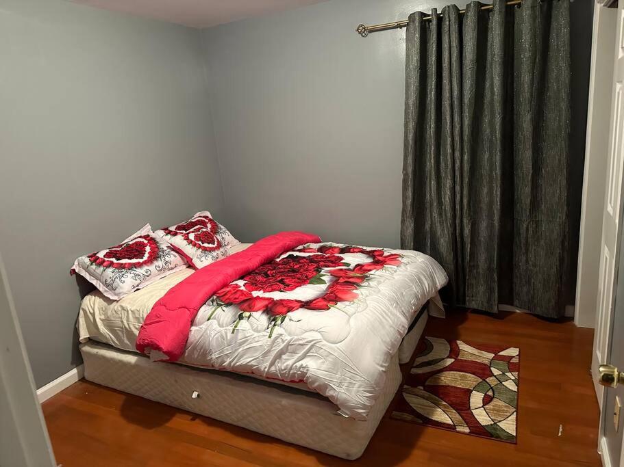 een slaapkamer met een bed met een rode en witte deken bij Glamour Room C 6mins to Newark Liberty International Airport and 3mins to Near Penn Station in Newark