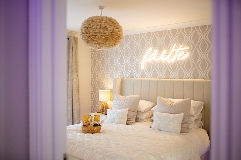 a bedroom with a white bed with a sign on the wall at The Koko Rooms in Inverness