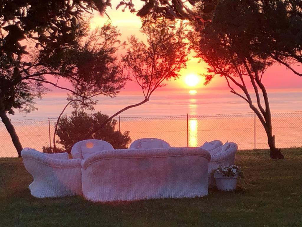 eine Couch im Gras mit Sonnenuntergang im Hintergrund in der Unterkunft Villa delle Fonti di Portonovo in Ancona