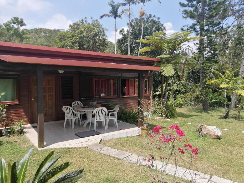 a cabin with a table and chairs on a porch at Maison en bois au Mont mou in Païta