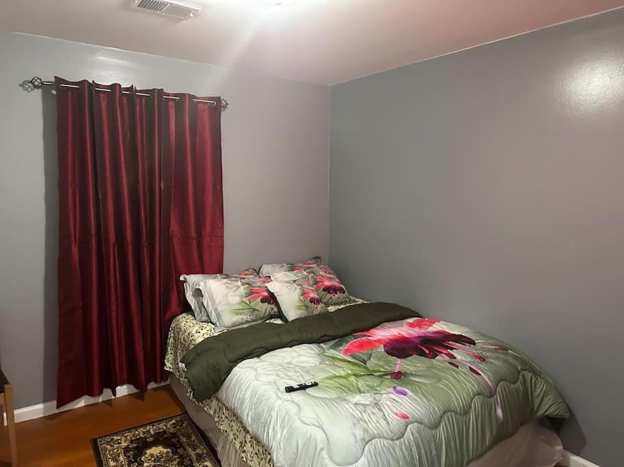 1 dormitorio con cama y cortina roja en Divine GUEST HOUSE Room B 6MINS TO NEAR Newark Liberty International Airport AND 4 MINS To Penn Station Prudential, en Newark