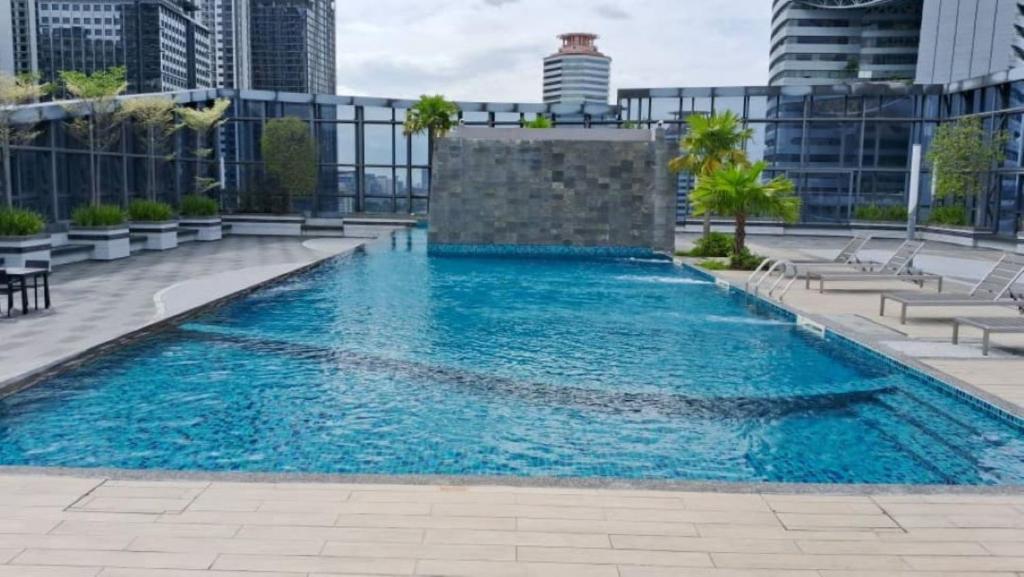 A rooftop swimming pool with loungers and Kuala Lumpur buildings beyond.