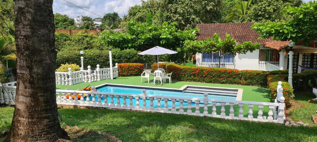 Un patio trasero con piscina y una cerca blanca. en Casa quinta La herradura valle verde, en Melgar