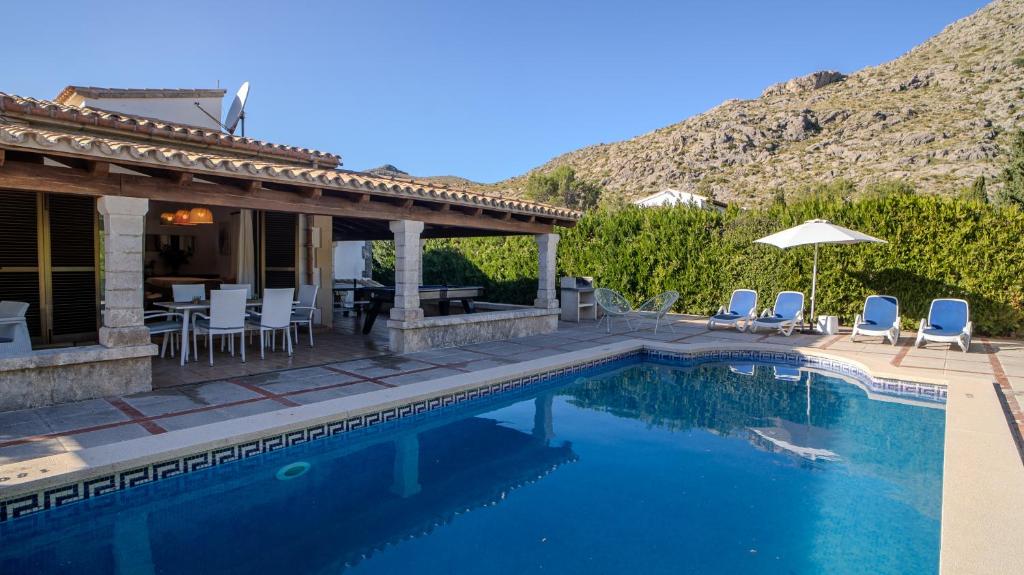 a swimming pool with chairs and a house at Villa Cal Peso in Port de Pollensa