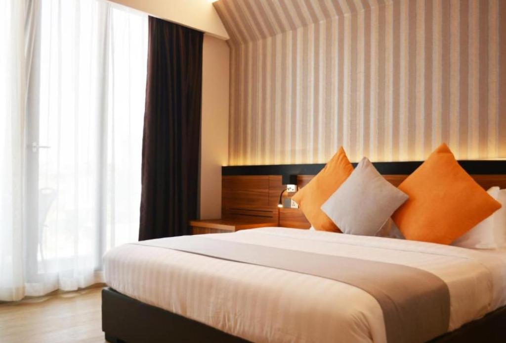 una camera d'albergo con un grande letto con cuscini arancioni di Hotel DHD - PAHARGANJ a Nuova Delhi