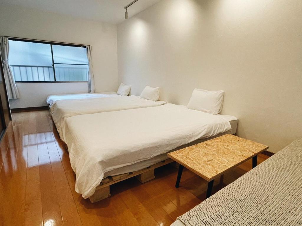 a small room with two beds and a table at UI HOUSE@南堀江 （1棟貸切り/難波まで2駅4分/京セラドーム徒歩圏内） in Osaka