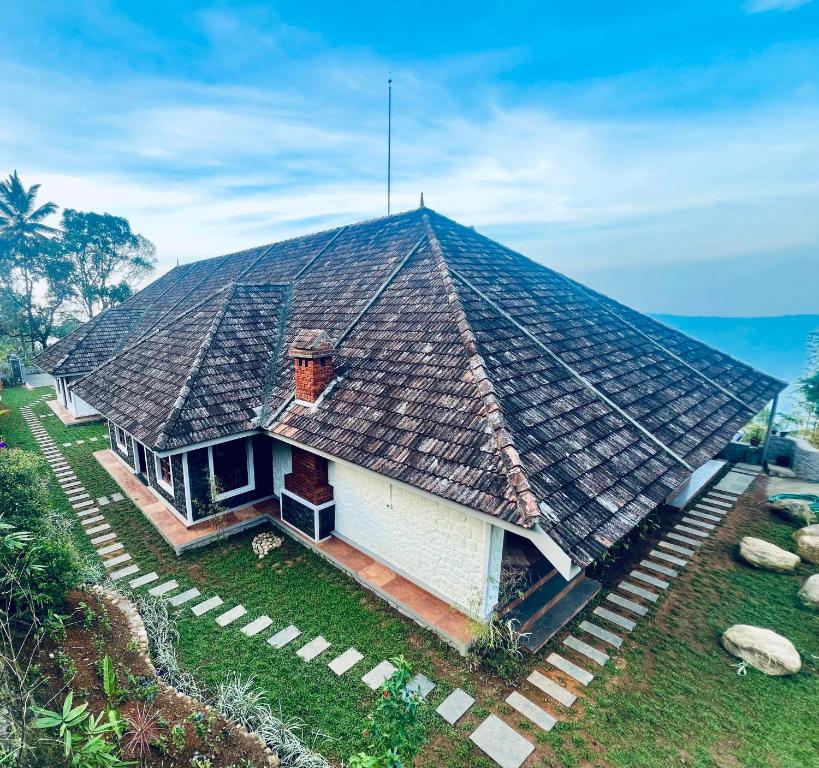 a house with a large roof on top of it at Nature Sanctuary Urumbi Hills in Mundakāyam