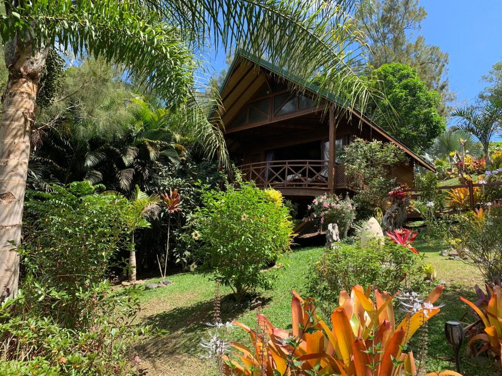 une maison avec un toit de chaume dans un jardin dans l'établissement Le Nirvana - Oasis de Tendéa - Farino, à Farino