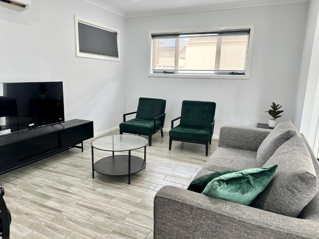 uma sala de estar com um sofá e duas cadeiras em Townhouse in West Footscray em Seddon