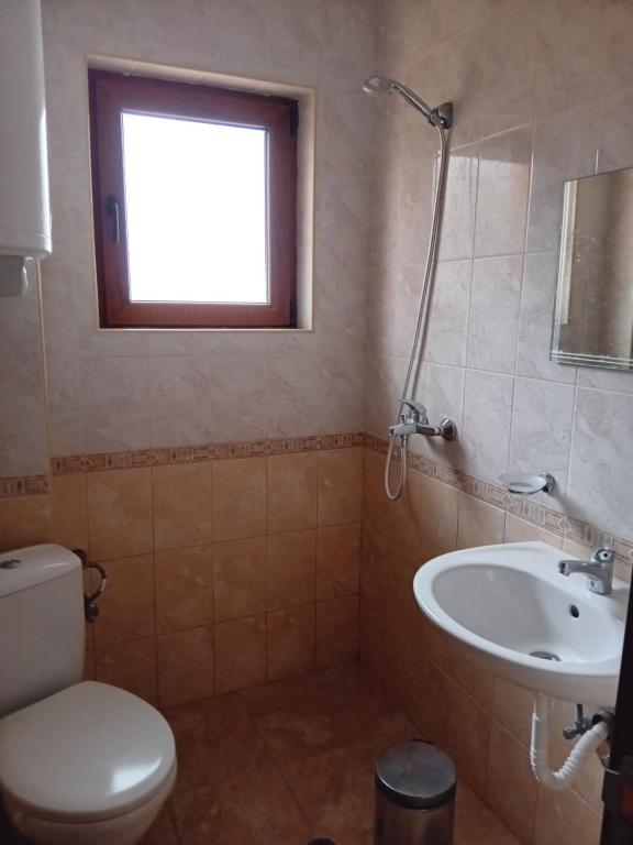a bathroom with a toilet and a sink and a window at Villa Mari Guest Rooms in Golden Sands