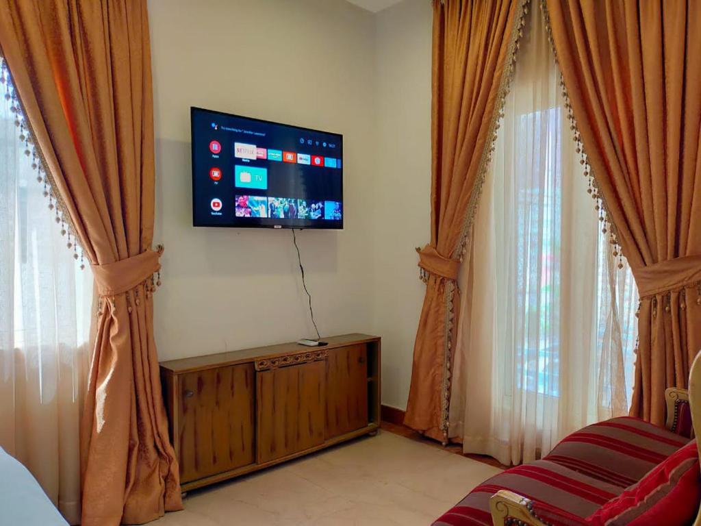 uma sala de estar com uma televisão de ecrã plano e cortinas em Noble Villa Hotel em Lagos