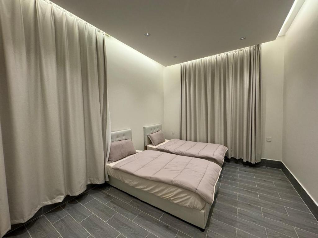 um quarto com uma cama com lençóis e cortinas cor-de-rosa em شاليه الرتاج الفندقي em Buraydah