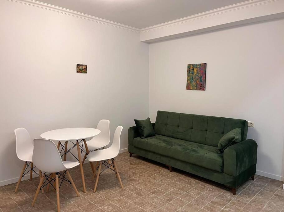 a living room with a green couch and a table at Cosy Apartment in Varketili in Samgori