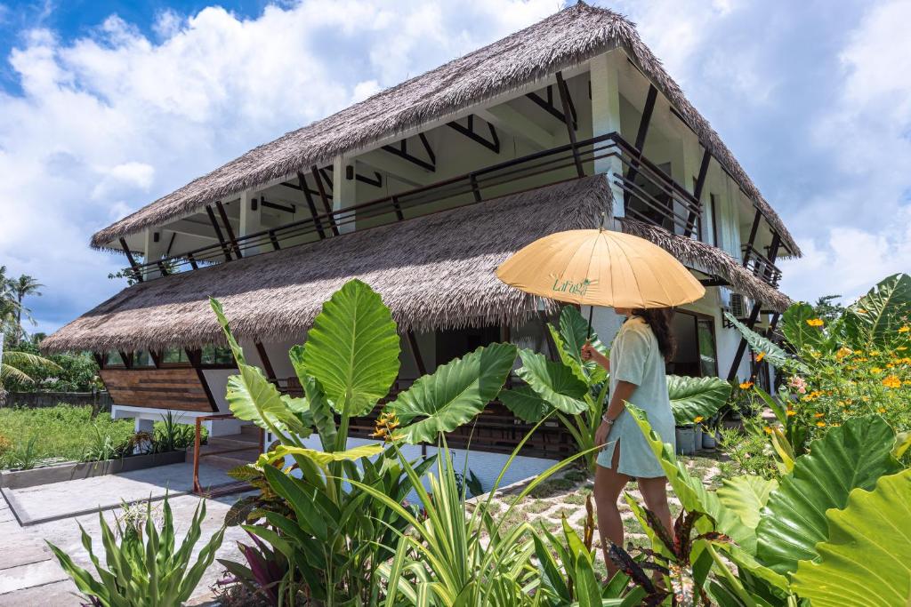 a person holding an umbrella in front of a building at La Fuga Siargao in Catangnan